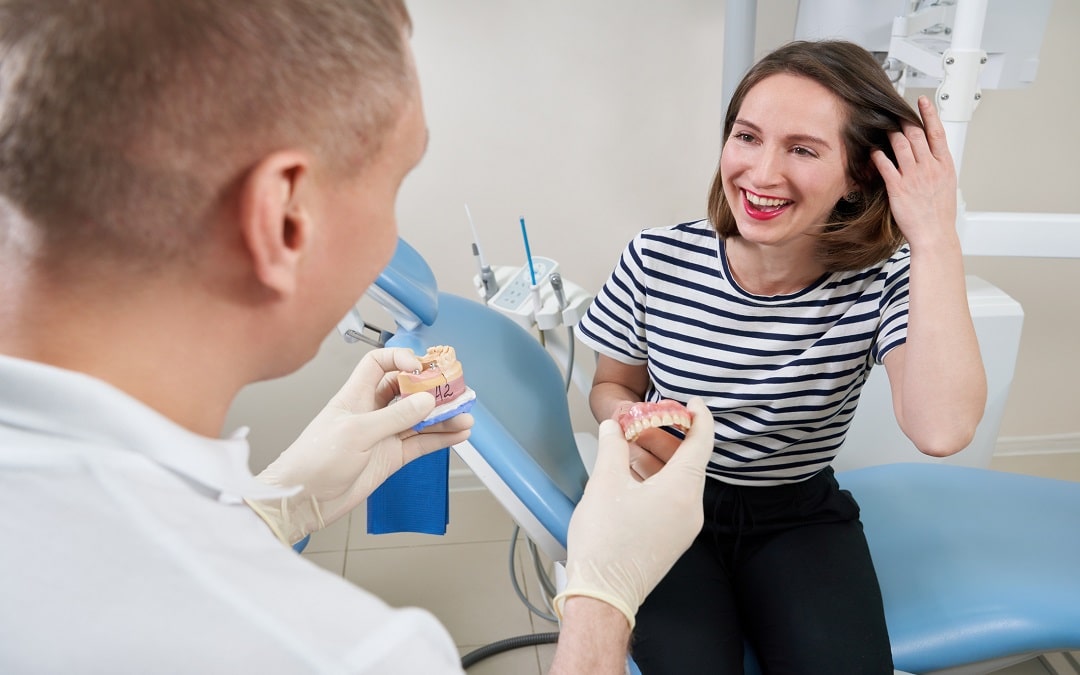 Male dentist showing his female patient a dental implant